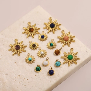 Vintage stainless steel sun pendants with colorful natural stones on marble surface