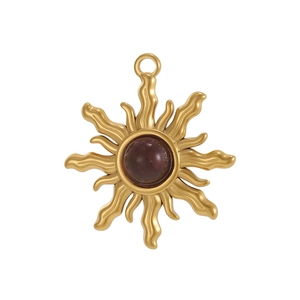 Macro view of gold stainless steel sunburst pendant featuring a center red stone inlay