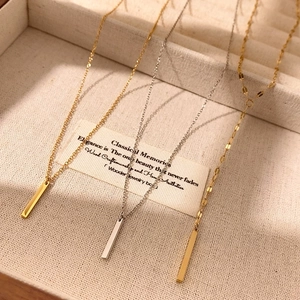 Three minimalist bar pendant necklaces in gold and silver finish displayed in a jewelry box
