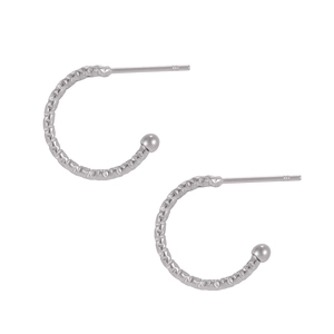 Detailed close-up of silver earrings with hammer texture and small ball decoration