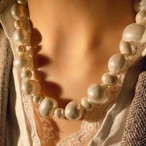 Gros plan d'un collier de perles multicouche avec haut en dentelle et blazer marron