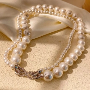 Gros plan d'un collier de perles double épaisseur avec fermoir infini argenté serti de diamants