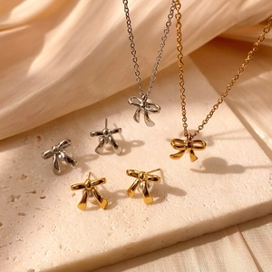 Nahaufnahme des gold- und silberfarbenen Schmucksets mit Schleifenanhänger und Ohrsteckern