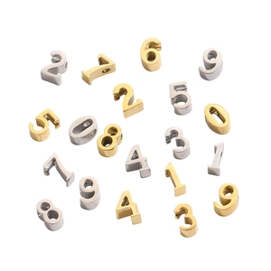 Detailed macro of 6mm gold and silver stainless steel 0-9 number pendants for DIY jewelry