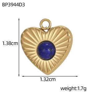 Macro shot of gold heart pendant with radial engraving and blue gemstone inlay