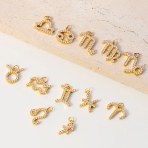 Detailed view of gold-plated zodiac charms with micro-paved cubic zirconia crystals
