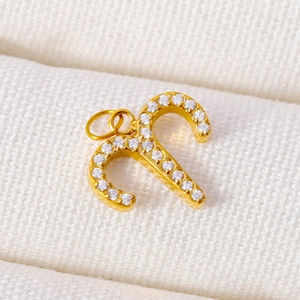 Macro shot of gold candy cane pendant with white pavé zircons and a top hanging ring