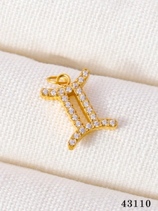 Macro shot of gold Gemini zodiac pendant with shimmering micro-pave crystals and ring attachment