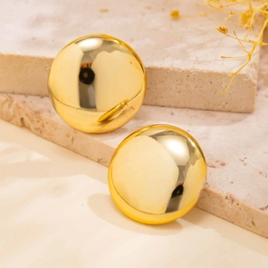 Polished gold dome earrings displayed on a textured stone surface with floral decor
