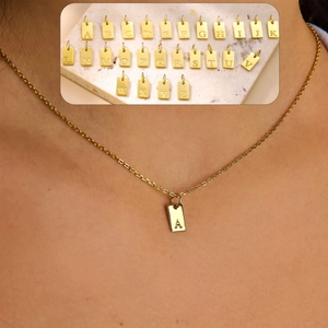 Detail of gold-plated rectangle letter pendants with engraved A-Z alphabet charms