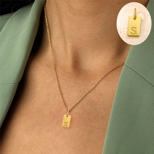 Detailed close-up of a 18K gold plated rectangular initial pendant with fine cross chain