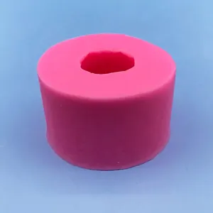 Stampo cilindrico in silicone rosa per candele a bocciolo di rosa su sfondo blu soft