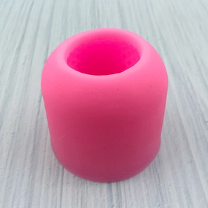 Draufsicht auf eine rosa zylindrische 3D-Vasen-Silikonform auf grauem Holzmaserungshintergrund