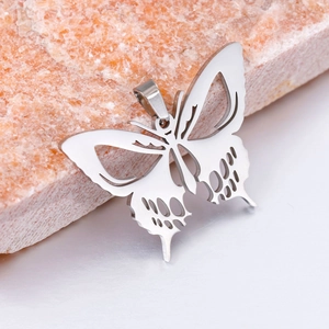 Detalle de un colgante de mariposa calado en acero inoxidable sobre una base de piedra