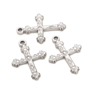 Detailed macro view of three silver stainless steel cross pendants with embossed patterns