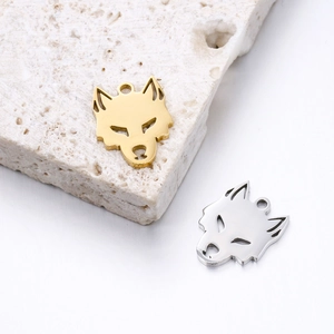 Détail de pendentifs tête de loup en acier inoxydable doré et argenté sur pierre
