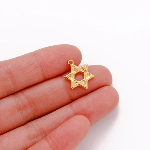 Macro shot of a gold-plated hexagram star pendant showing fine embossed details and texture