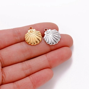 Polished gold and silver stainless steel shell pendants held in hand for jewelry making