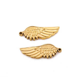 Macro detail of gold stainless steel angel wing charms with delicate feather textures