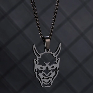Vue macro du pendentif masque Hannya en acier inoxydable avec cornes et fini oxydé