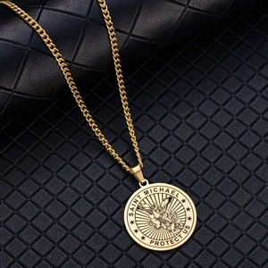 Macro shot of gold Saint Michael pendant with Saint Michael Protect Us engraving details