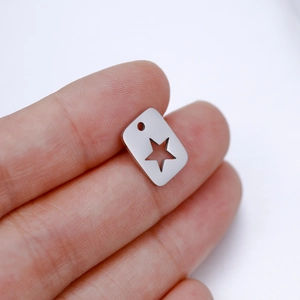 Macro view of polished stainless steel rectangle charm with cutout star held by fingers