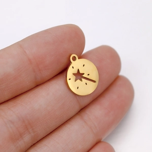 Gold hollow star magic wand pendant in stainless steel held to show miniature size