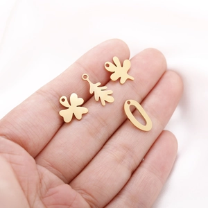 Close-up of golden stainless steel leaf and irregular wave pendants on a white fabric