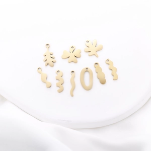 Macro view of gold leaf and wave pendants showing brushed texture and hole details