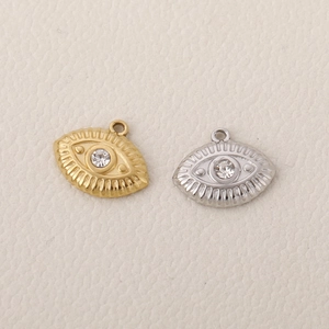 Macro detail of gold and silver evil eye pendants with sparkling center zircon stones