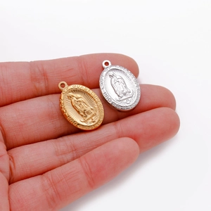 Pendentifs ovales Vierge Marie de Guadalupe en or et argent posés sur la main