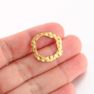 Macro detail of irregular gold metal charm with hammered texture for DIY jewelry making