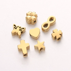 Close-up of golden stainless steel DIY beads in heart, clover, and butterfly shapes