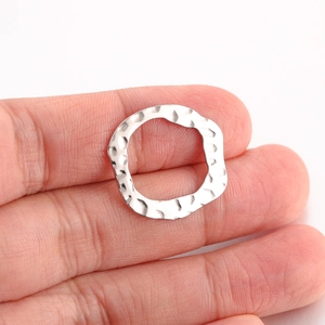 Macro view of silver irregular hammered round charm showing handmade texture and details