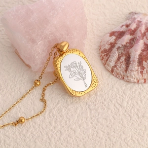Detalle de un colgante cuadrado vintage dorado con incrustación floral y cadena de bolas