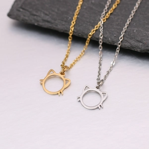 Gros plan de pendentifs tête de chat minimalistes en acier inoxydable doré et argent