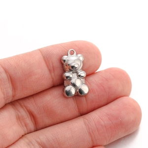 Detailed close-up showing the small scale of a polished stainless steel teddy bear charm