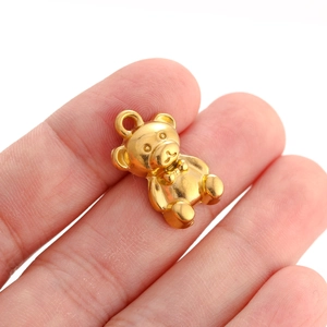 Detailed close-up of a 3D golden teddy bear pendant held to show its compact DIY size