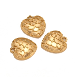 Macro view of matte gold heart charms with intricate fish scale pattern and metal texture