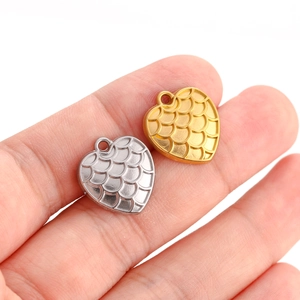 Retro heart pendants in gold and silver steel with scale texture held in hand