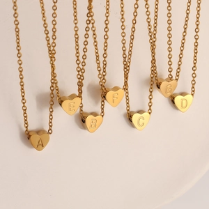 Detalle de collares en forma de corazón dorado con colgantes de letras iniciales grabadas