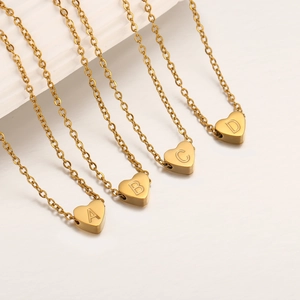 Detalle de cuatro colgantes de corazón en acero dorado con letras grabadas A, B, C y D