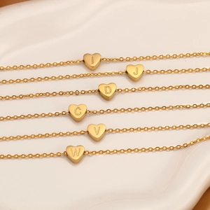 Detalle de varios collares con colgantes de corazón dorados e iniciales grabadas