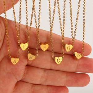 Primer plano de colgantes de corazón en acero inoxidable dorado con letras grabadas