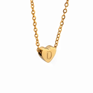 Primer plano del colgante de corazón dorado con letra D grabada en una cadena fina