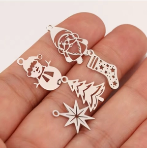 Handheld view of stainless steel hollow Christmas pendants with snowman and tree motifs