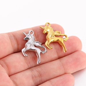Détail de breloques licorne 3D dorées et argentées tenues en main pour montrer la taille
