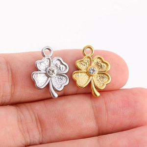 Détail de pendentifs trèfle en argent et or avec pétales texturés et cristaux centraux