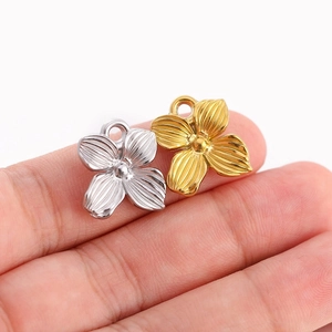 Gros plan de breloques fleurs à quatre feuilles argent et or pour bijoux DIY
