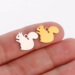 Close-up of small squirrel charms in gold and silver finish showing compact size on finger